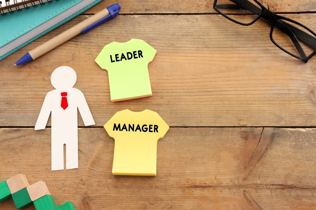 Paper cutout figure with leader and manager labels on sticky notes, illustrating organizational roles and hierarchy