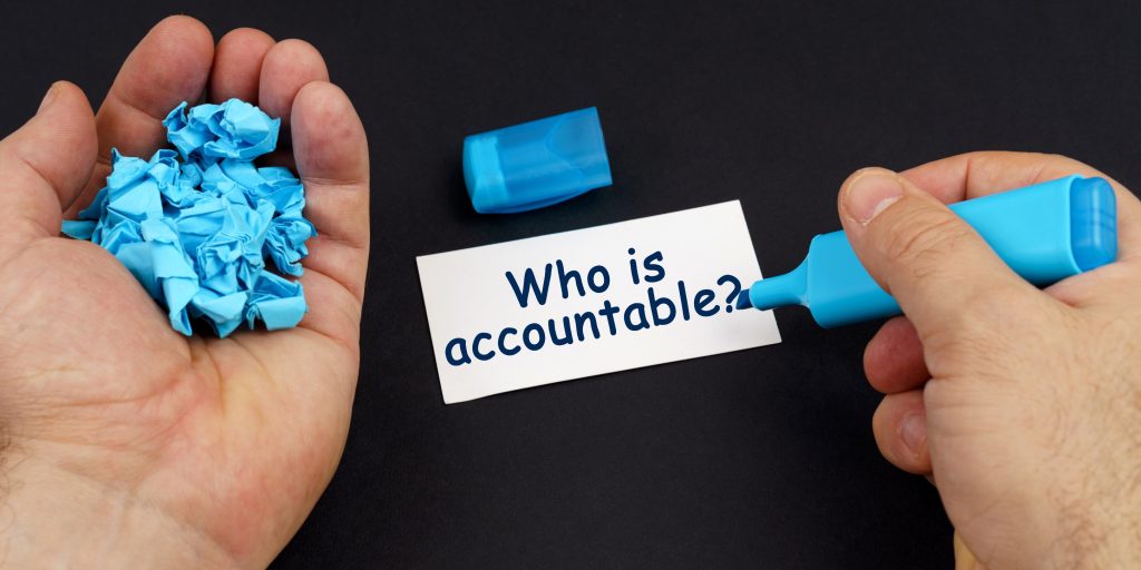 Two hands holding crumpled blue paper with "Who is accountable?" text, representing leadership responsibility