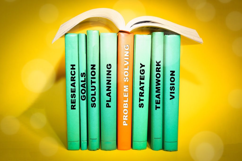Five green books about leadership stacked to form an open book shape against a yellow background