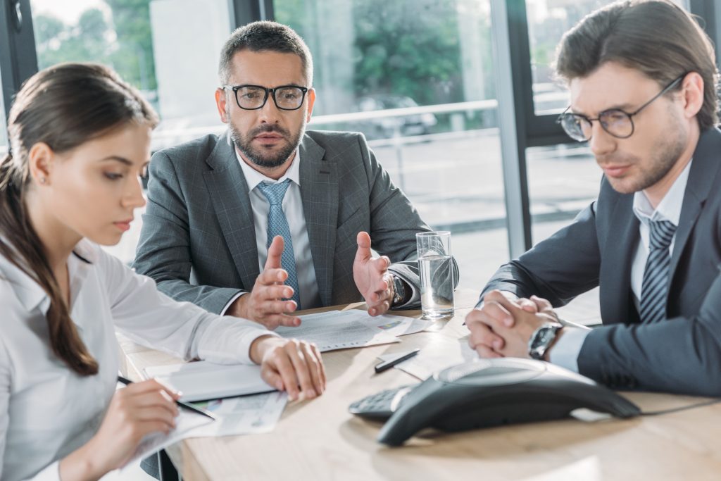 Three business professionals reviewing documents during a workplace meeting