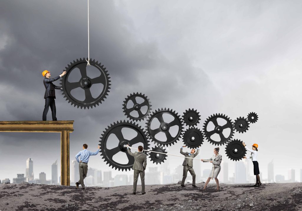 Team of professionals assembling interconnected gears, symbolizing collaborative problem-solving and organizational
