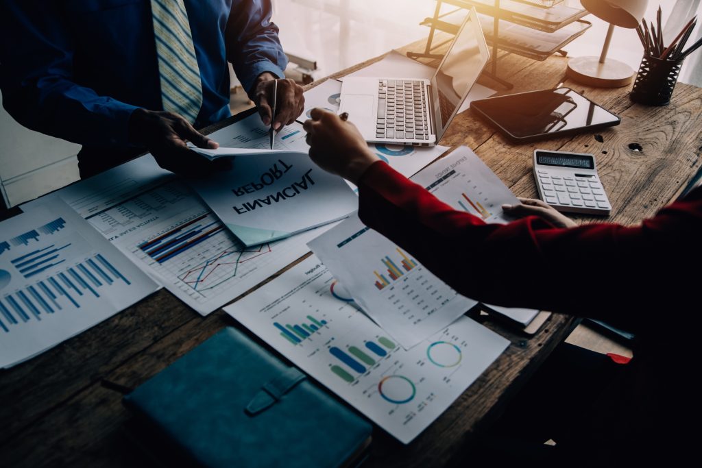 Business owner and advisor reviewing financial documents and analytics to identify and resolve operational issues before