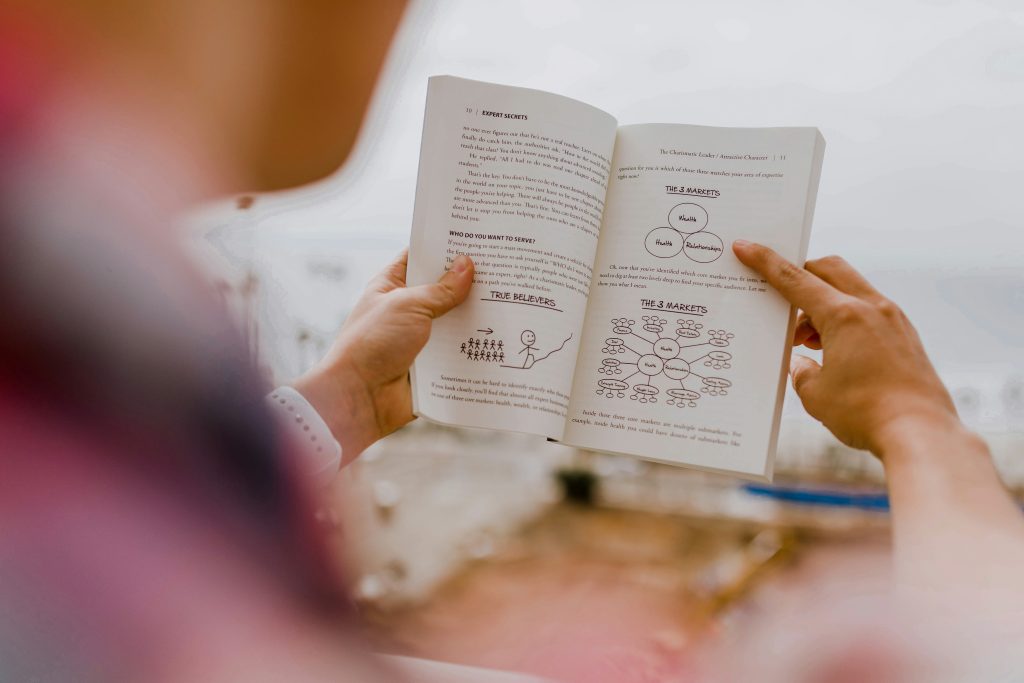 Person reading open book or manual on scaling business systems and culture