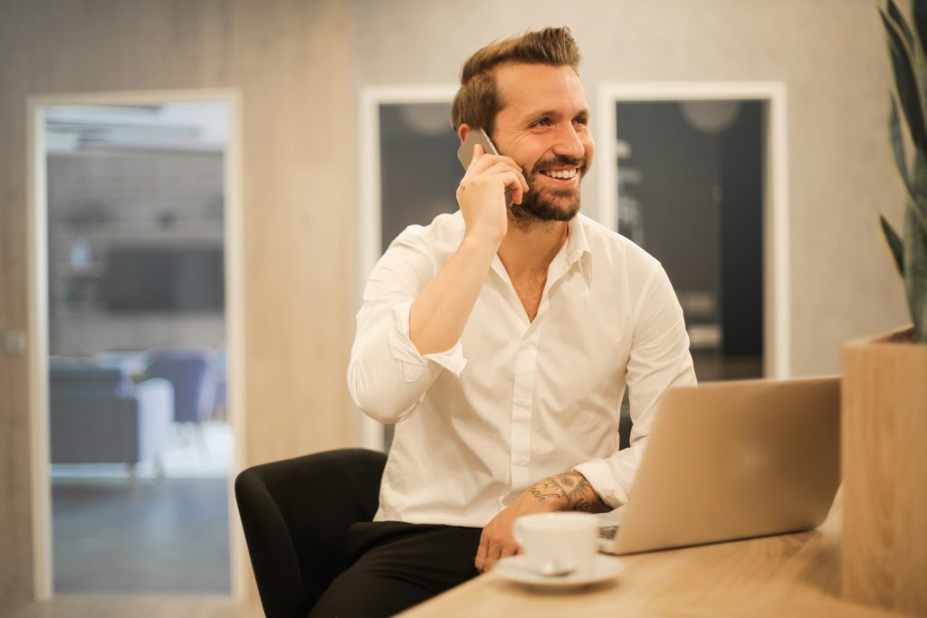 Professional man on phone call at laptop in modern office setting