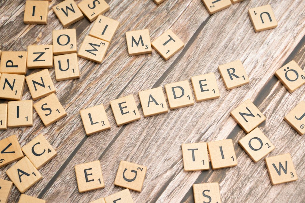 Scrabble tiles spelling "LEADER" on wooden surface, representing business leadership and clarity