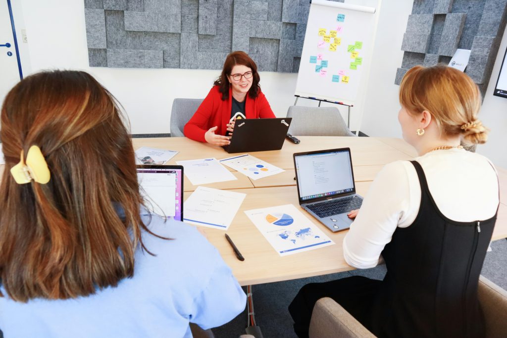 Three professionals in a business meeting discussing sales performance and team accountability
