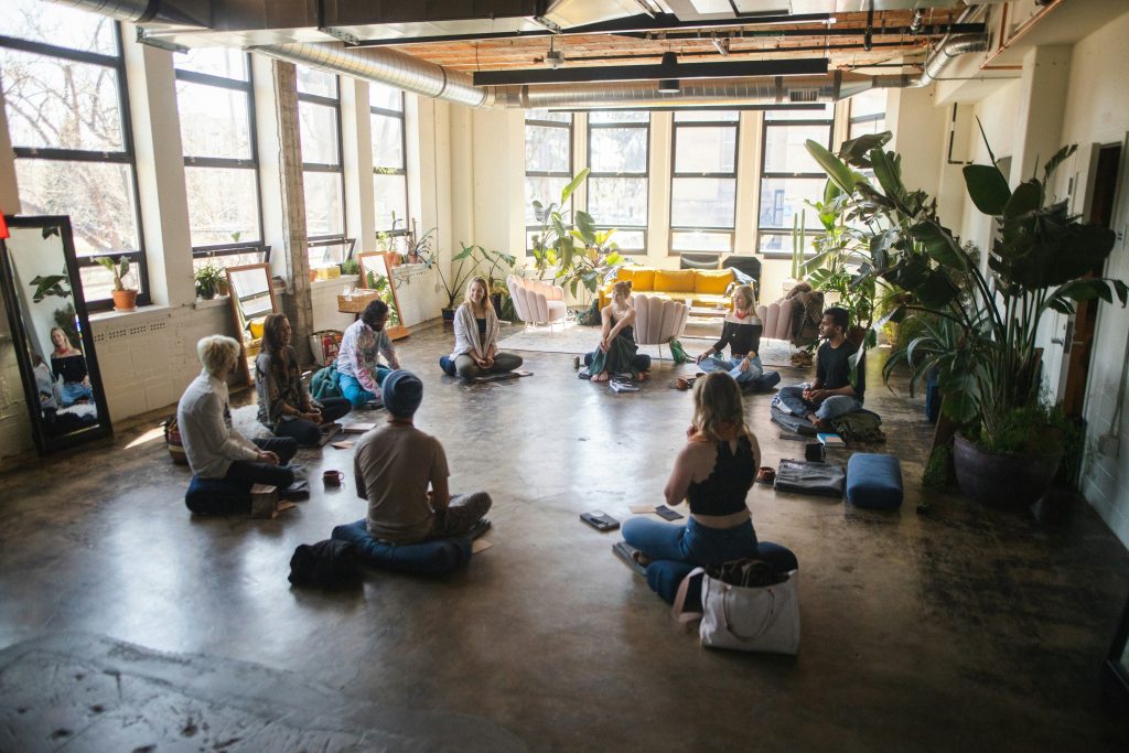 Group of employees practicing meditation or yoga together in a bright, plant-filled office space