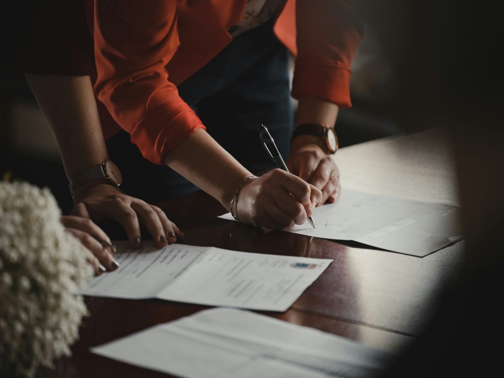 Two professionals reviewing signed documents and paperwork together at a desk, representing the critical handoff between