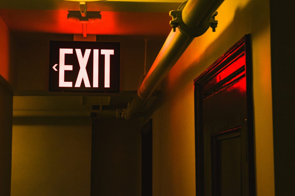 Illuminated exit sign in warm-lit corridor symbolizing business transition and exit strategy planning