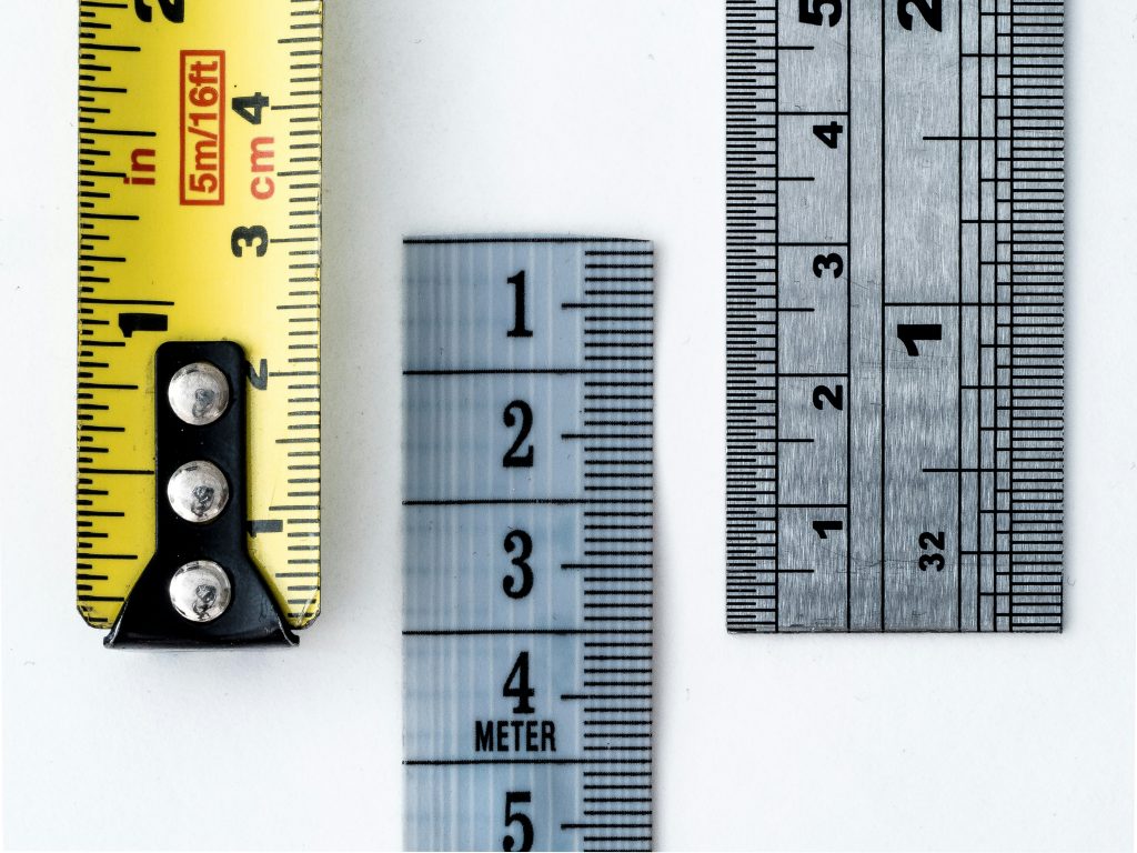 Three measuring rulers displaying numbered scales, symbolizing metrics tracking and measurement for business growth