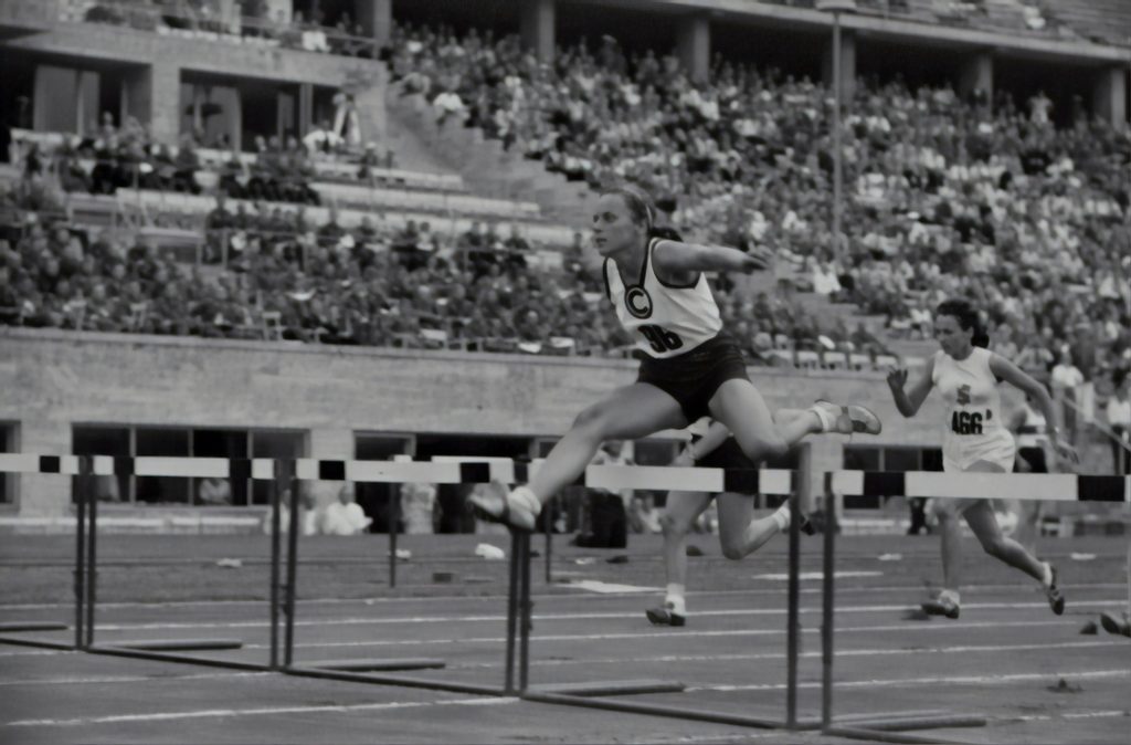 Athlete clearing hurdle in stadium race, symbolizing overcoming business obstacles with speed and agility