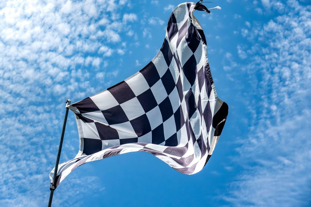 Checkered flag waving against blue sky, symbolizing finish line and winning momentum