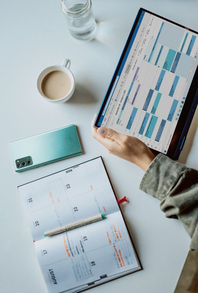 Person reviewing strategic planning documents and digital analytics dashboard on tablet while referencing printed calendar