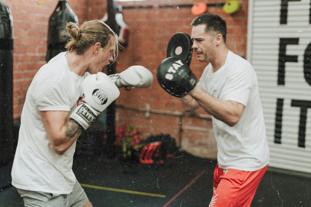 Two professionals sparring in boxing gloves, demonstrating opposing perspectives through physical engagement